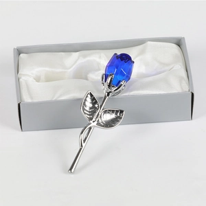 Gros plan d'une rose en cristal bleu dans un coffret cadeau gris avec doublure en satin blanc