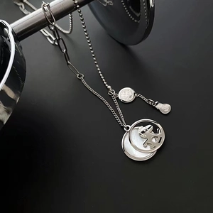 Titanium steel layered necklace with white mother-of-pearl pendant on a metal stand
