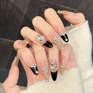 Macro detail of almond press-on nails with black French tips, crystals, and pearls
