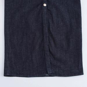 Dettaglio della trama in denim blu scuro e bottone metallico sulla parte anteriore