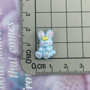 Close-up of a 2cm blue resin rabbit figurine with yellow bow for DIY crafts