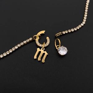Detail view of gold stainless steel tennis chain with letter M and round crystal charms.