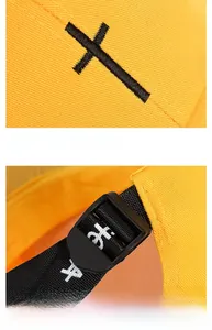 Close-up of yellow cotton baseball cap featuring black cross embroidery and adjustable strap