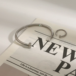Silver stainless steel nail bracelet and ring set with rhinestones on newspaper background