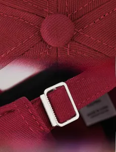 Macro shot of burgundy baseball cap showing cotton twill fabric and silver metal buckle