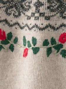 Detailed view of beige knit sweater with geometric jacquard and floral embroidery