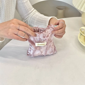 Close-up of hands opening a pink lace textured drawstring bag for small item storage