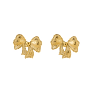 Gros plan de boucles d'oreilles nœud dorées élégantes montrant la texture du métal