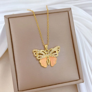 Close-up of golden butterfly necklace with pink wings and sparkling zircons
