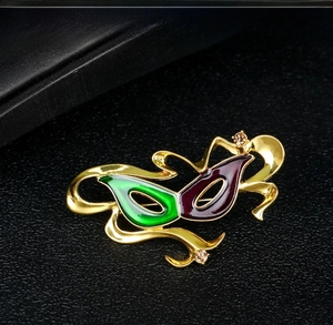 Detail of face mask brooch with colorful enamel eyes and amber rhinestones
