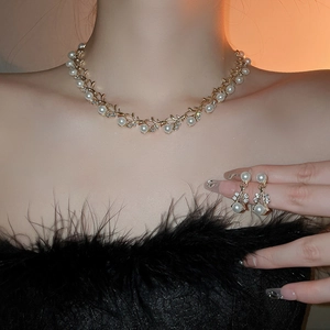 Close-up of gold vine pearl necklace and matching earrings worn by a model