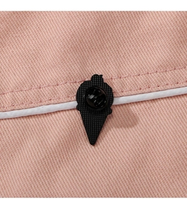 Close-up of cute cartoon penguin ice cream enamel pin on pink denim fabric texture