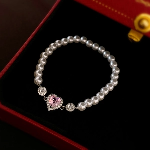Detailed shot of sweet pink heart zircon and white pearl bracelet in a red gift box