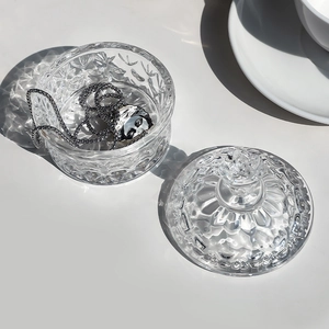 Embossed floral glass jewelry box with lid and elegant shadow on white background