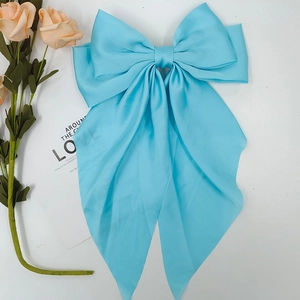 Detailed view of large light blue satin bow hair clip with elegant long flowing ribbons