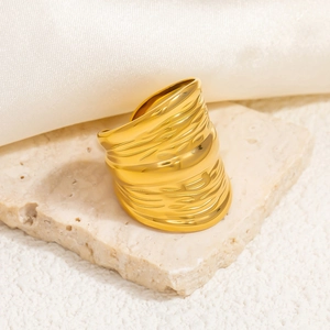 Macro shot of gold-plated stainless steel ring on beige stone and silk background