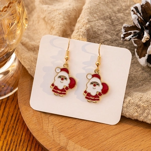 Detail of Christmas Santa Claus earrings with red and white enamel finish on wood base