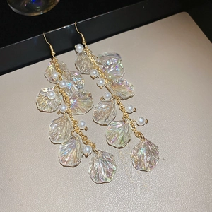 Detail view of long tassel earrings with iridescent petals and pearls on leather display