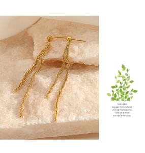 Detail shot of long golden tassel earrings with woven chain texture on stone base