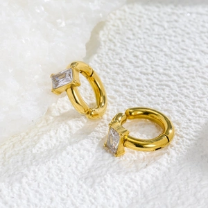 18k gold plated hoop earrings with rectangular zircon stone on white textured surface