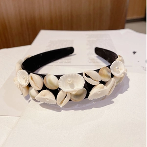 Detail of baroque headband with natural shells and white pearls on black fabric base