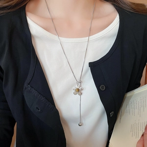 Detail view of silver flower lariat necklace with brown stone on a female model