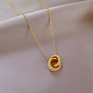 Macro shot of interlocking gold and crystal rings on pink silk luxury jewelry necklace