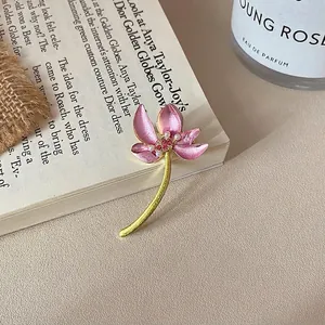 Detail of pink enamel flower brooch with rhinestones and white pearls on golden stem