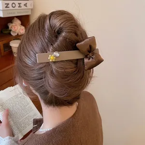 Floral bow hair clip with matte khaki base and rhinestones shown on model in warm setting