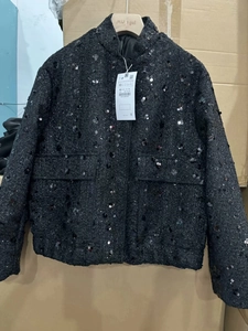 Detail shot of a black sequin tweed jacket featuring a stand collar and front flap pockets