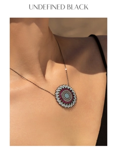 Macro detail of sunburst pendant featuring blue pavé diamonds and violet marquis gems