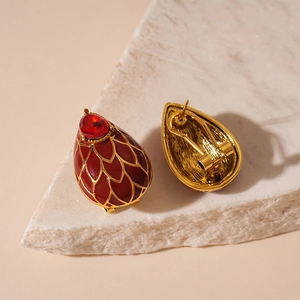 Détails macro des boucles d'oreilles vintage en émail rouge avec motifs dorés