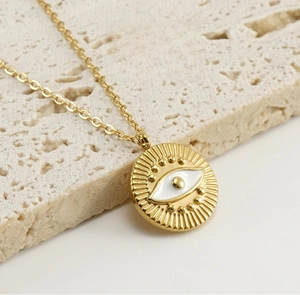 Macro shot of 18k gold plated evil eye necklace with detailed white enamel and fine chain