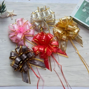 Detail of colorful metallic gift pull bows in pink, gold, and silver on a rustic wood surface
