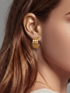 Gros plan de boucles d'oreilles créoles dorées en C ajourées portées par un mannequin
