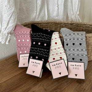 Détail des chaussettes tricotées rétro avec motifs cœurs dans un panier en osier