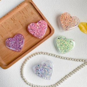 Detailed view of heart-shaped glitter phone grips in various pastel colors on leather
