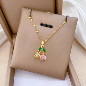 Close-up of cherry pendant necklace with pink crystal and zircon inlay in jewelry box