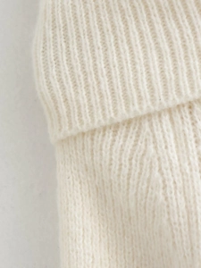Vue macro de la texture en maille côtelée blanc ivoire et du tissage doux de ce pull en maille