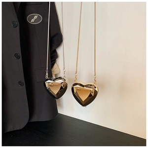 Detail of diamond-cut heart evening bags in black and gold with sleek metal chain straps