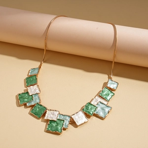 Detail of geometric enamel necklace with gold chain and green marble patterned tiles