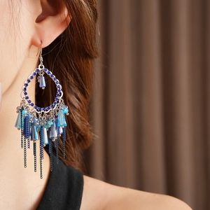 Dettaglio di orecchini a nappa blu con cristalli su modella per un look vintage