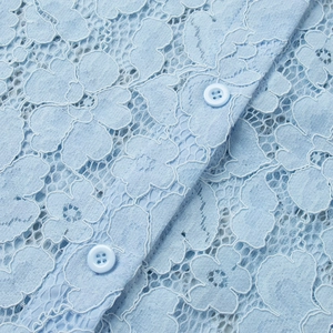 Close-up of light blue floral lace fabric with matching resin buttons on shirt detail
