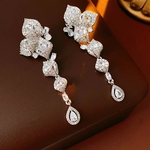 Gros plan sur des boucles d'oreilles fleur en zircon avec pompons sur cuir brun