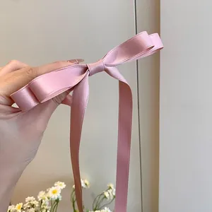 Close-up of pink satin bow hair clip with long ribbons and delicate fabric texture