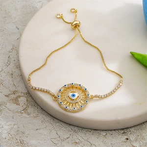 Detail view of gold adjustable bracelet with evil eye heart charm and zircon stones