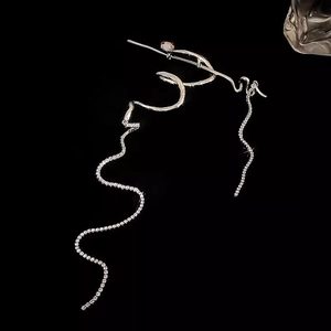 Detail of silver snake earrings with sparkling rhinestone tassels on black background