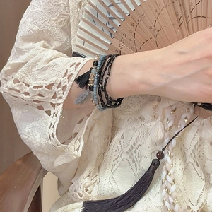 Close-up of bohemian multilayer beaded bracelet with grey tassels and vintage charms