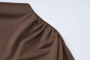 Close-up detail of dark brown ruched fabric texture with fine stitching on women's dress