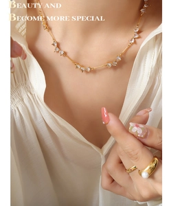 Detail of heart zircon necklace and pearl gold ring on elegant silk fabric